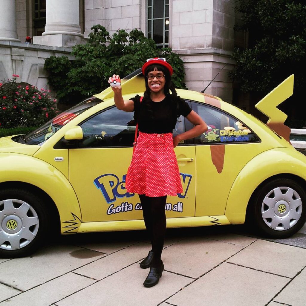 Me as Serena from Pokémon posing in front of a VW beetle that looks like Pikachu